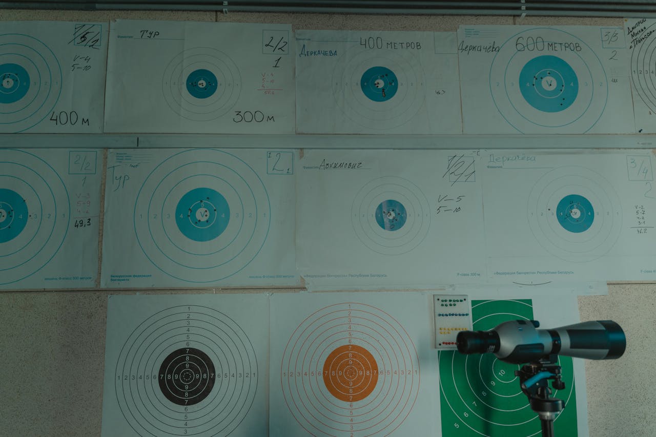 services-02 Image of a target shooting setup with a spotting scope and displayed target papers indoors.